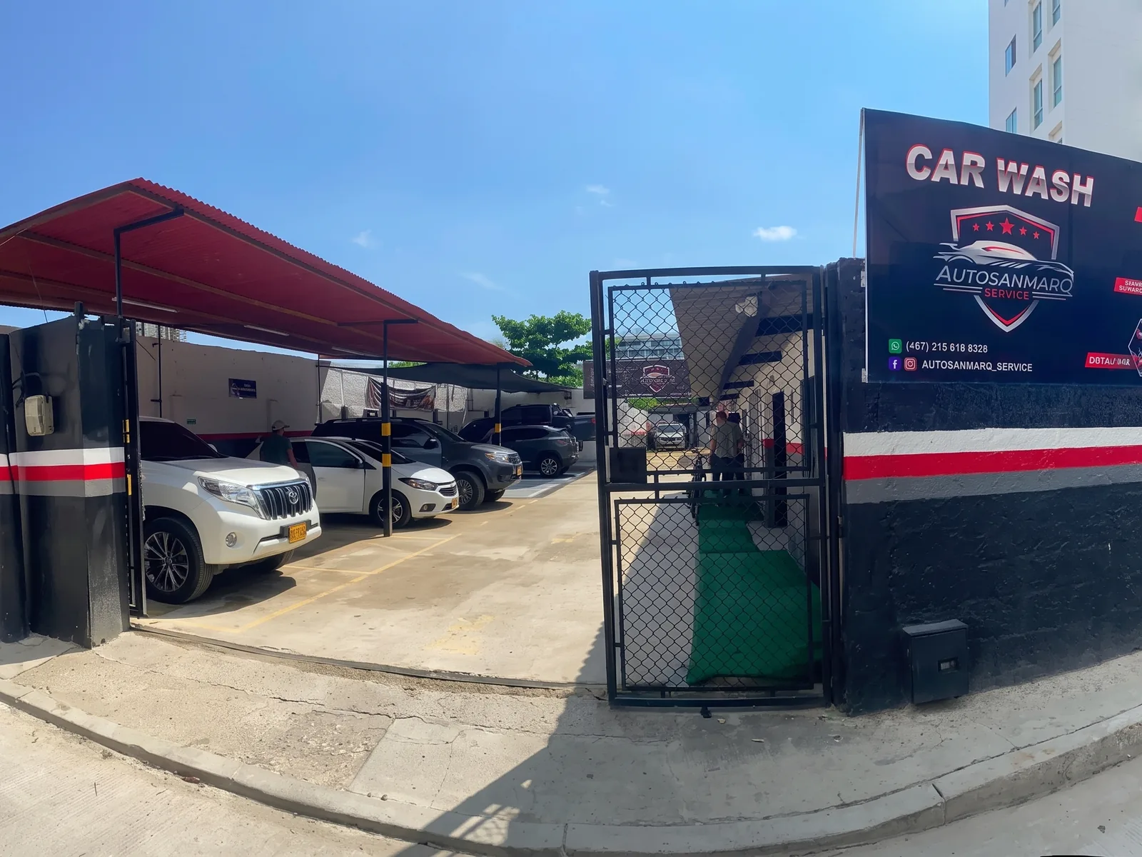 Fachada del taller AutosanmarQ Service en Marbella: techo rojo, portón y el aviso de car wash